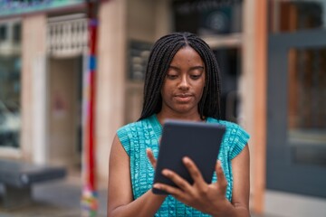 African american woman using touchpad with serious expression at street