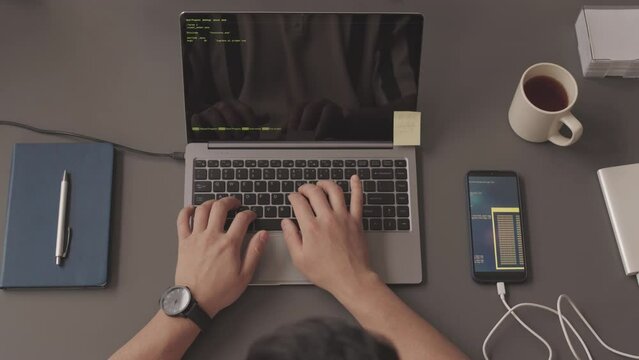 Top view slowmo of hands of unrecognizable programmer writing program code on laptop at office desk