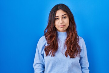 Obraz premium Hispanic young woman standing over blue background depressed and worry for distress, crying angry and afraid. sad expression.