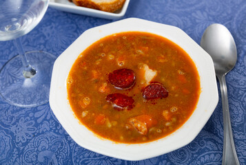Bowl of lentils stew with vegetables, meat and sausages. Popular dish of spanish and cuban cuisine