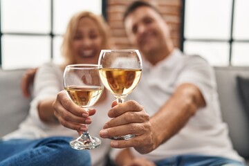 Middle age man and woman hugging each other toasting with champagne at home