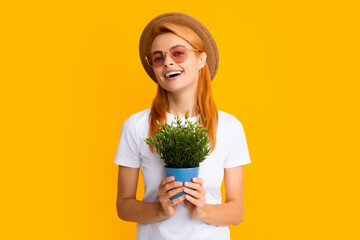 Summer gardener woman isolated on yellow background. Redhead funny girl planting flowers in pot.