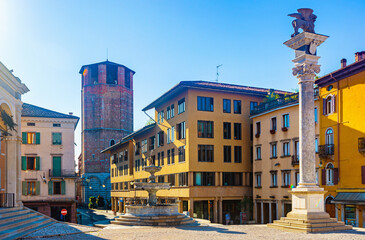 Fototapeta na wymiar View of Piazza liberta - central square of Udine city with ancient fountain and Column bearing Venetian Lion, Italy
