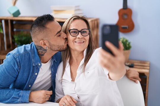 Man and woman mother and son make selfie by smartphone kissing at home