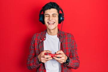 Young hispanic man playing video game holding controller celebrating crazy and amazed for success...