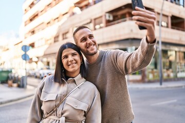 Naklejka premium Man and woman couple smiling confident making selfie by the smartphone at street