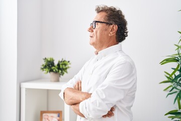 Middle age man standing with serious expression and arms crossed gesture at home