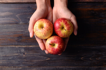 Red apple fruit holding by hand on wooden background, Table top view, Healthy fruit