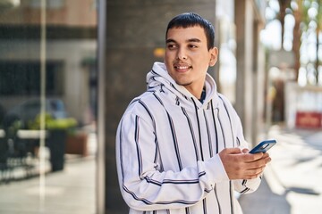 Young man smiling confident using smartphone at street