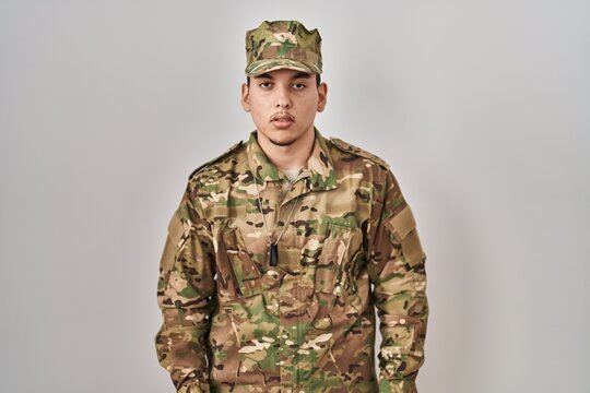 Young arab man wearing camouflage army uniform looking sleepy and tired, exhausted for fatigue and hangover, lazy eyes in the morning.