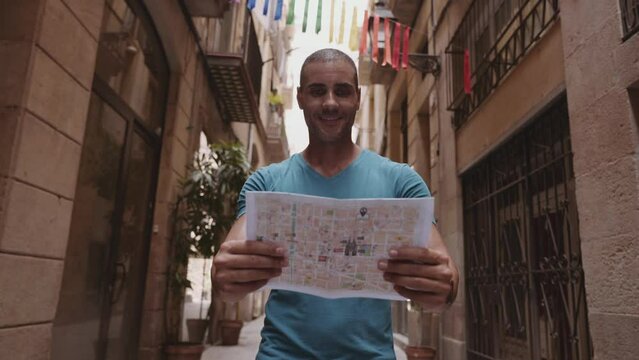 Happy male tourist maps user walking in old town alley an using a map. Barcelona, Spain. Cinematic 4K