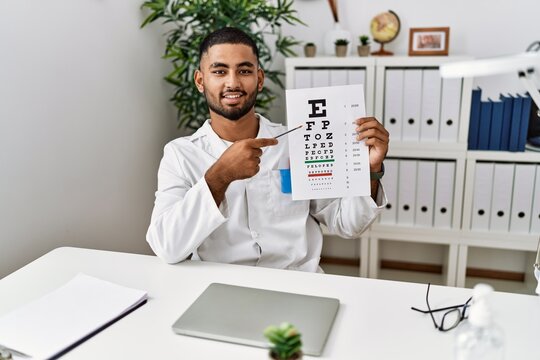 Young middle east man wearing optician uniform testing vision at clinic