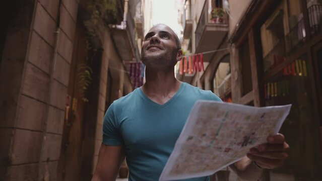 Happy male tourist maps user walking in old town alley an using a map. Barcelona, Spain. Cinematic 4K