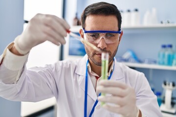 Young hispanic man scientist measuring liquid at laboratory