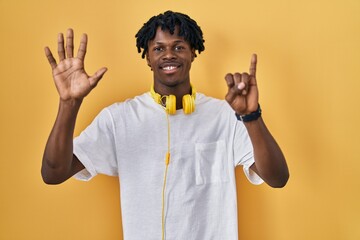 Young african man with dreadlocks standing over yellow background showing and pointing up with fingers number six while smiling confident and happy.