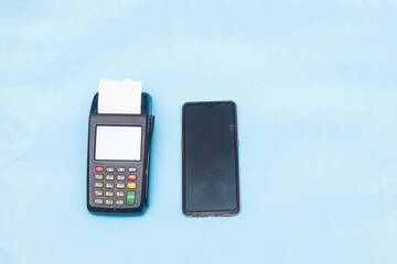 closeup of mobile smartphone and pos machine place on a blue background