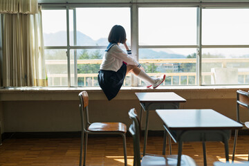 Fototapeta premium 窓際で外を見る女子高生