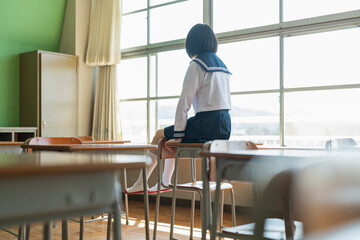 机の上に座る女子高生