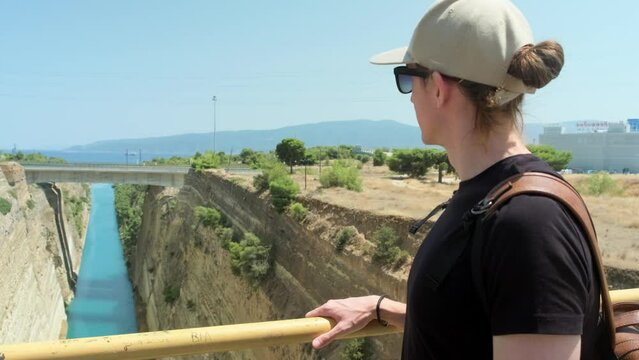 Traveling man looking at view of Corinth canal, Peloponnese, Greece.