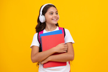 School girl, teenage 12, 13, 14 years old in headphones and books on isolated studio background. School kids with backpack.