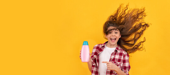 happy teen girl with long curly hair hold shampoo bottle, beauty. Banner of child girl hair care, studio poster header with copy space.