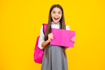 Excited face. Schoolgirl, teenage student girl hold book on yellow isolated studio background. School and education concept. Back to school. Amazed expression, cheerful and glad.