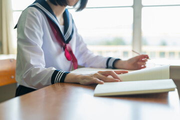 隣の席の友人に教科書を見せる女子高生