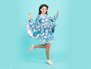 Naklejka premium Happy teenager, positive and smiling emotions. Happiness, freedom, motion and child. Young teenager girl jumping over blue background, funny jump.