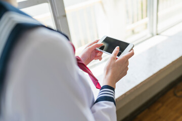 教室 スマートフォンでゲームをする女子高生