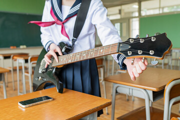 教室 ギターのチューニングをする女子高生