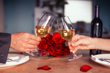 Couple on a dinner date enjoying a glass of wine next to red roses 