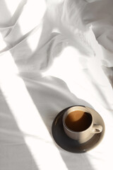 Cup of aromatic coffee on bed in morning, above view. Space for text