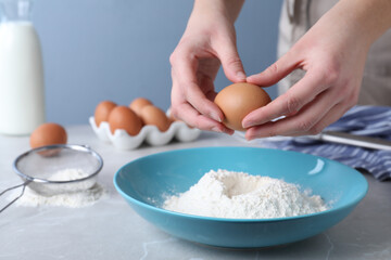 Woman preparing batter for thin pancakes at light grey table, closeup