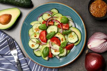 Tasty salad with cucumbers served on grey table, flat lay