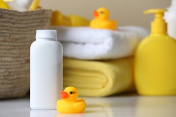 Obraz na płótnie Canvas Bottle of dusting powder and rubber duck on white table, space for text. Baby cosmetic product