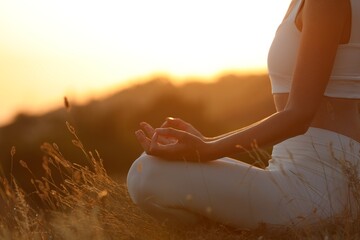 Woman meditating outdoors at sunset, closeup view
