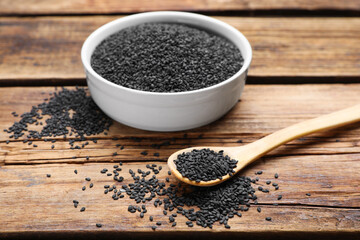 Bowl and spoon with black sesame on wooden table