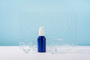 Cosmetic cream metallic pump bottle mockup on blue background with stylish props, glass balls and...