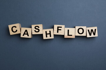 Wooden cubes with phrase Cash FLow on grey background, flat lay