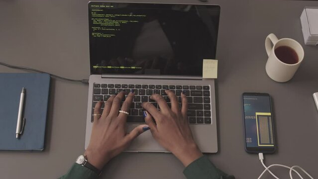 Top view slowmo of hands of unrecognizable African American female programmer writing program code on laptop