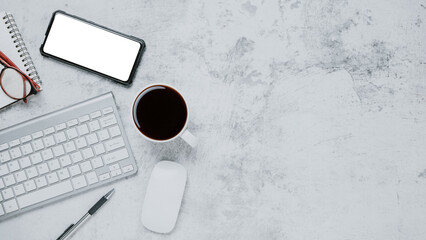 Top view, White Office desk with computer keyboard, eyeglass, Blank screen smart phone, pen, notebook and cup of coffee, copy space, Mock up.