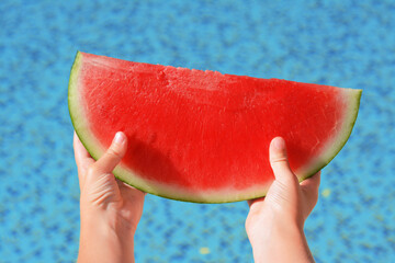 Child holding fresh juicy watermelon near swimming pool outdoors, closeup