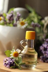 Bottle of natural lavender essential oil near mortar with flowers on wooden table