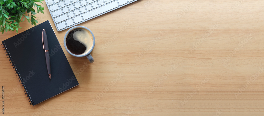 Poster simple workplace with wireless keyboard, notebook and coffee cup on wooden table. top view with copy