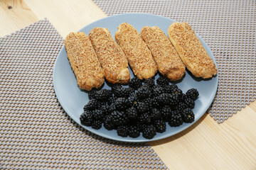 eclairs and blackberries on a blue plate
