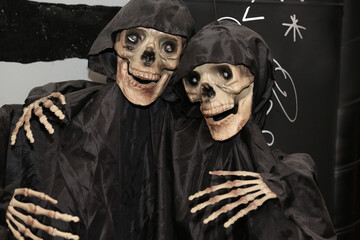 two decorative skeletons in black raincoats for halloween