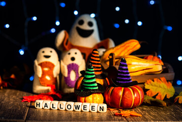 Festive Halloween image. Pumpkins, boo toys, autumn leaves on a wooden table.