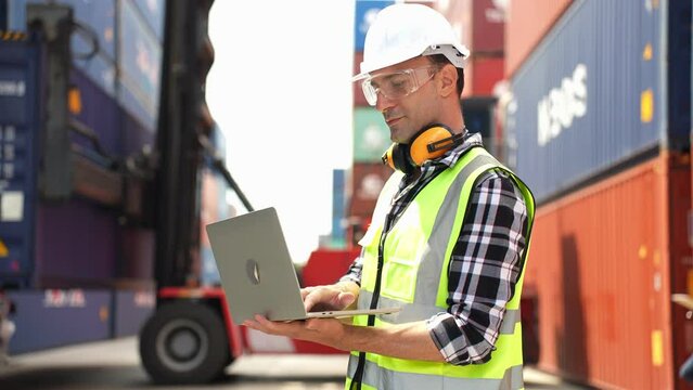 Caucasian engineer male working with laptop in container port terminal