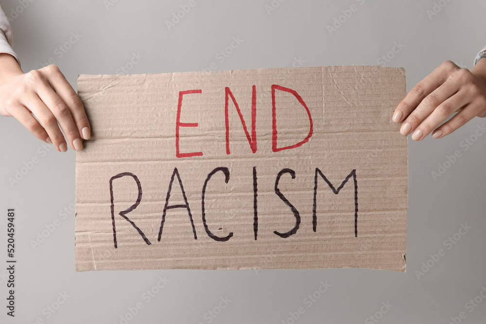 Wall mural hands holding piece of carton with text end racism on grey background