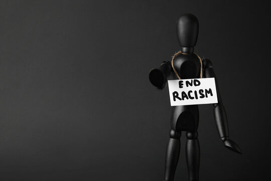 Black mannequin and paper sheet with text END RACISM on dark background
